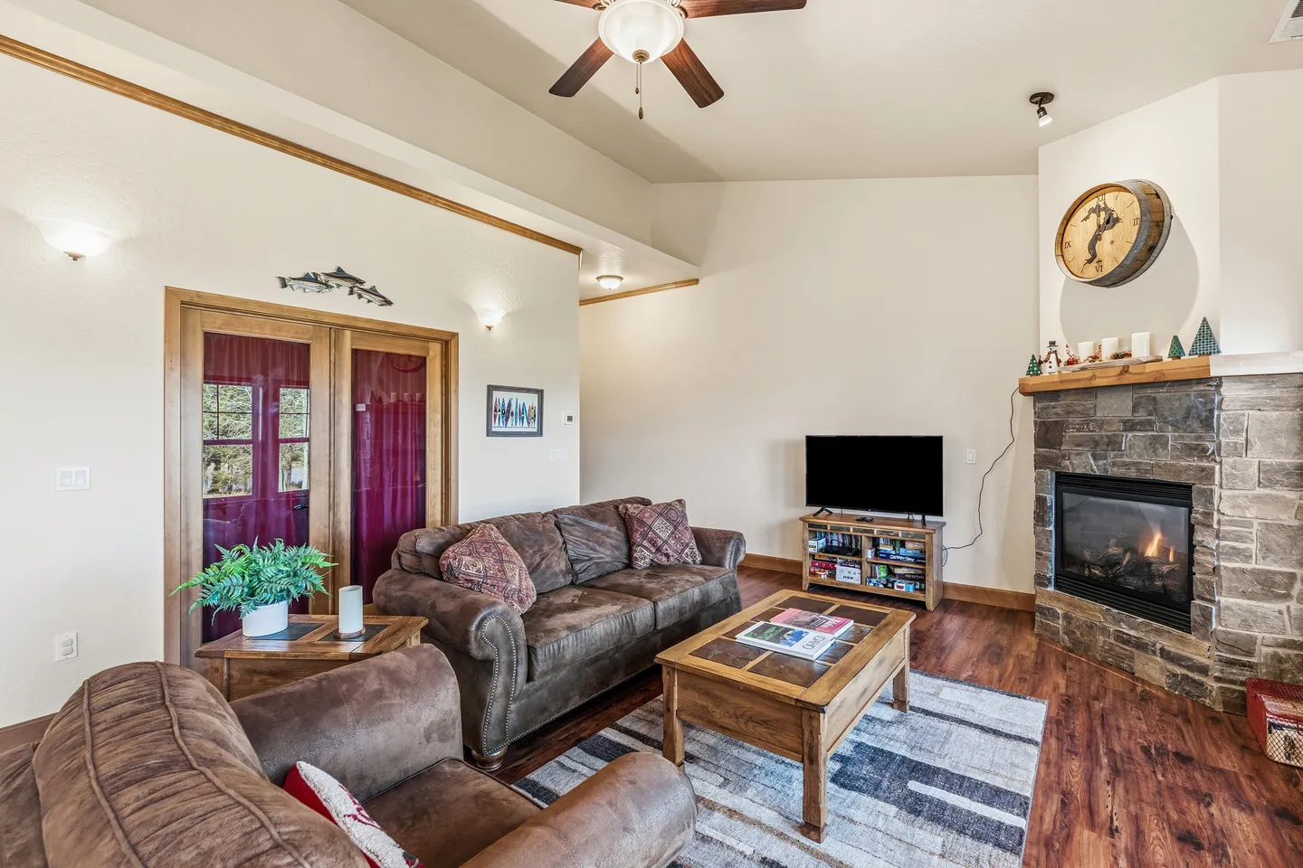 Living room with plush seating, wood coffee table, TV stand, and stone corner fireplace.