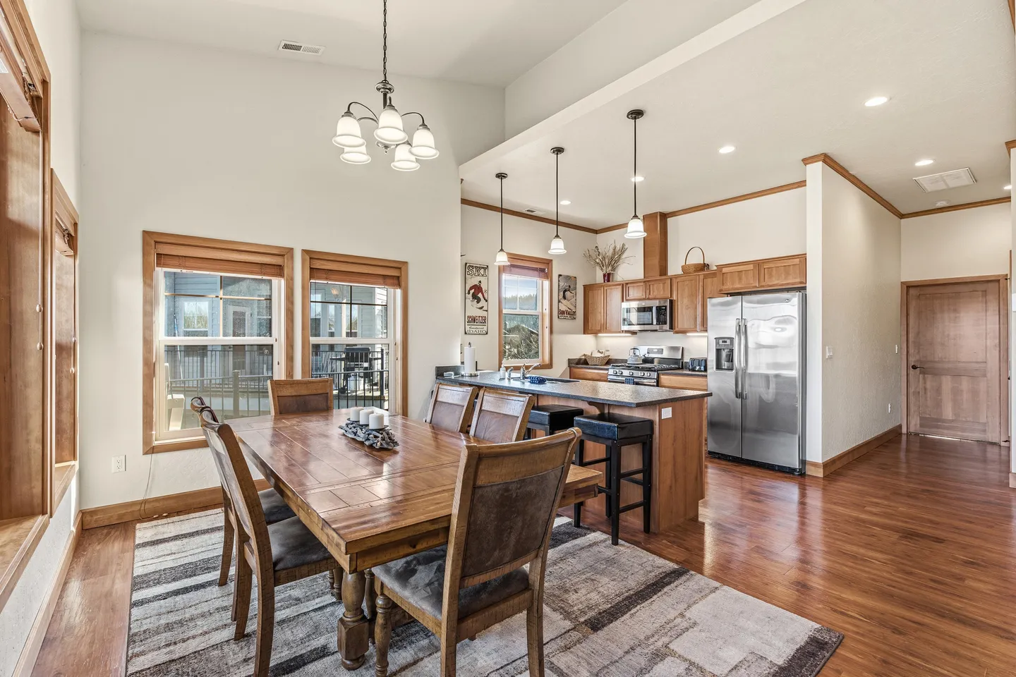 Open concept dining area and kitchen with wooden dining table, wood cabinetry, and stainless steel appliances.