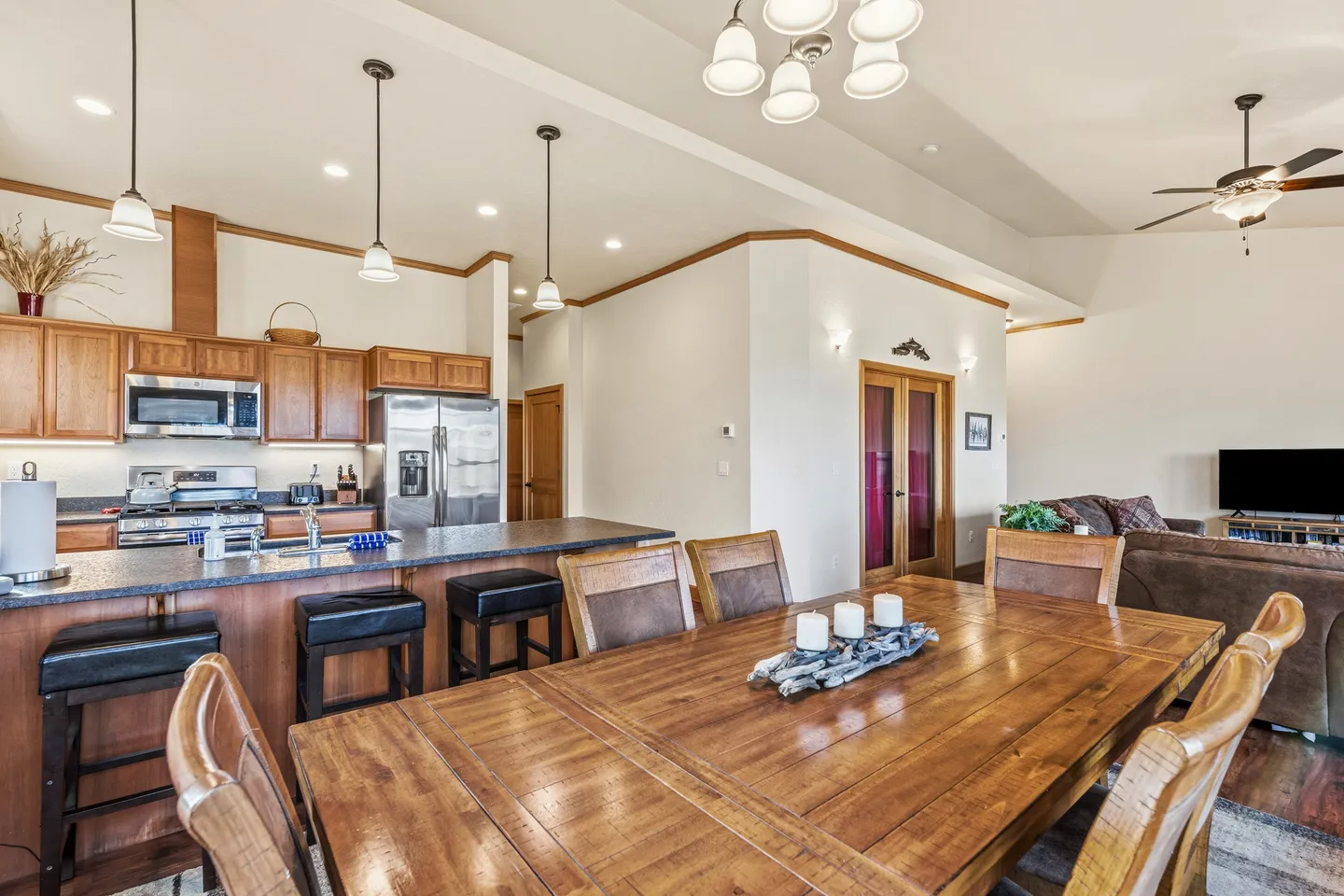 Open-concept dining area with a wooden table, opening directly into the kitchen with island seating and the living room.