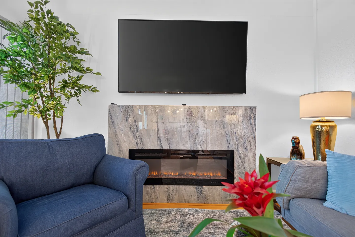 A living room seating area featuring an electric fireplace beneath a wall-mounted flat-screen television.