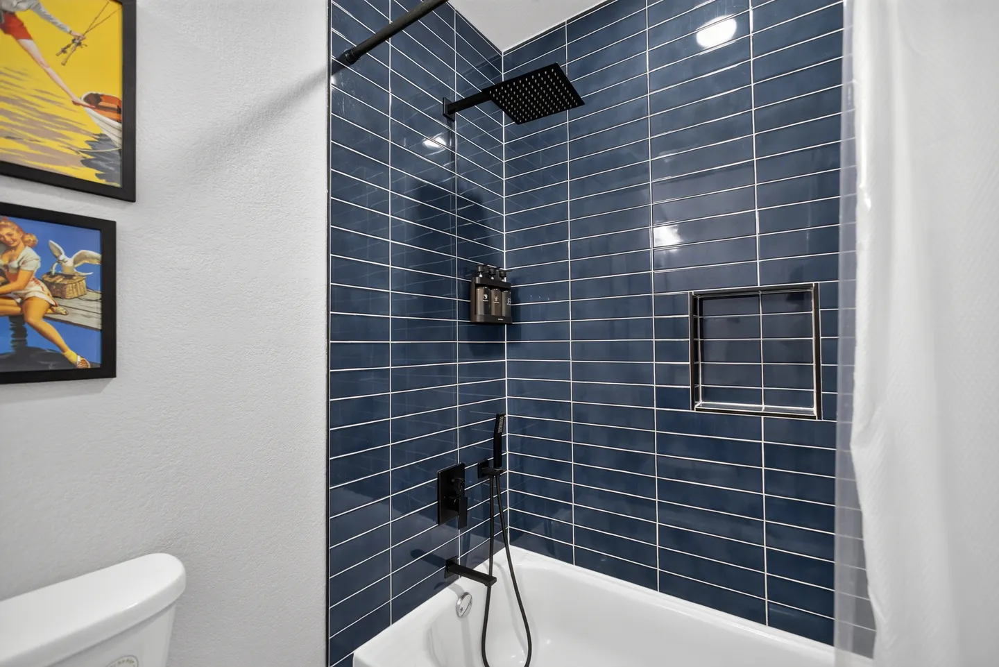 Bathroom tub and shower combination with deep blue subway tile and matte black fixtures.