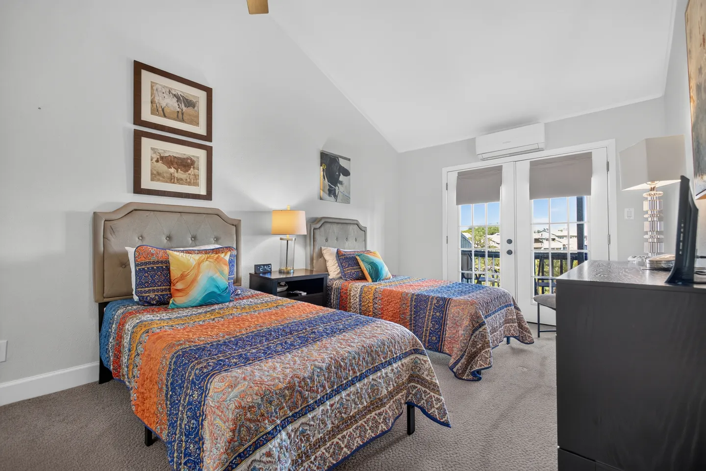Bedroom with two twin beds featuring colorful patterned quilts and French doors leading out to a balcony.
