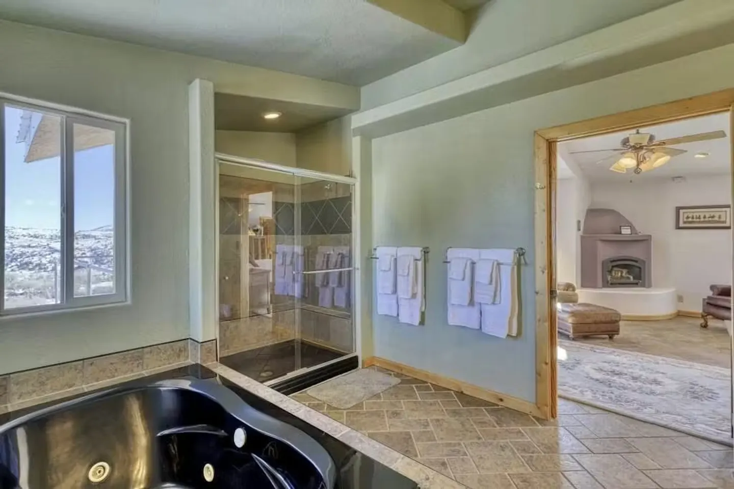 Bathroom featuring a black soaking tub, tiled shower with glass door, and an open doorway into an adjoining bedroom.