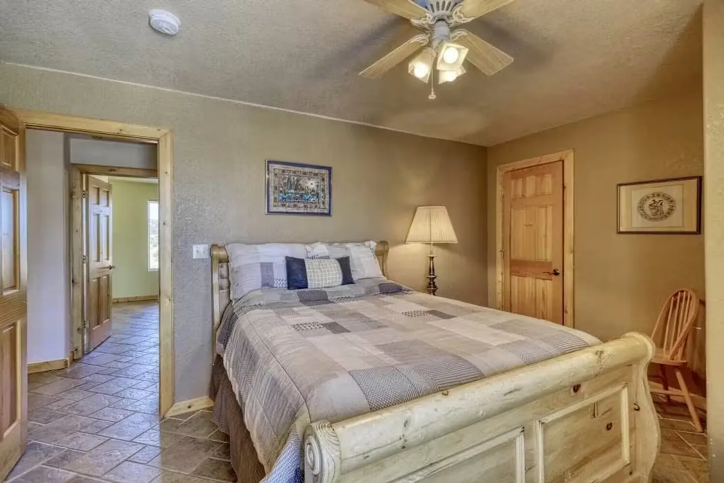 Bedroom featuring a wooden sleigh bed, tiled floors, a lighted ceiling fan, and doorways leading to other rooms.