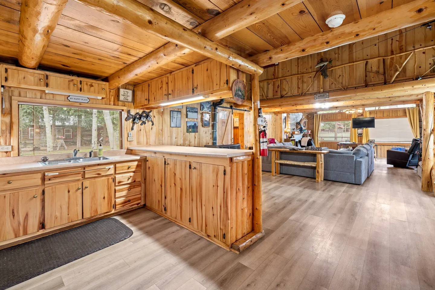 Open-concept cabin interior looking from the kitchen with wood cabinetry toward the adjoining living area.