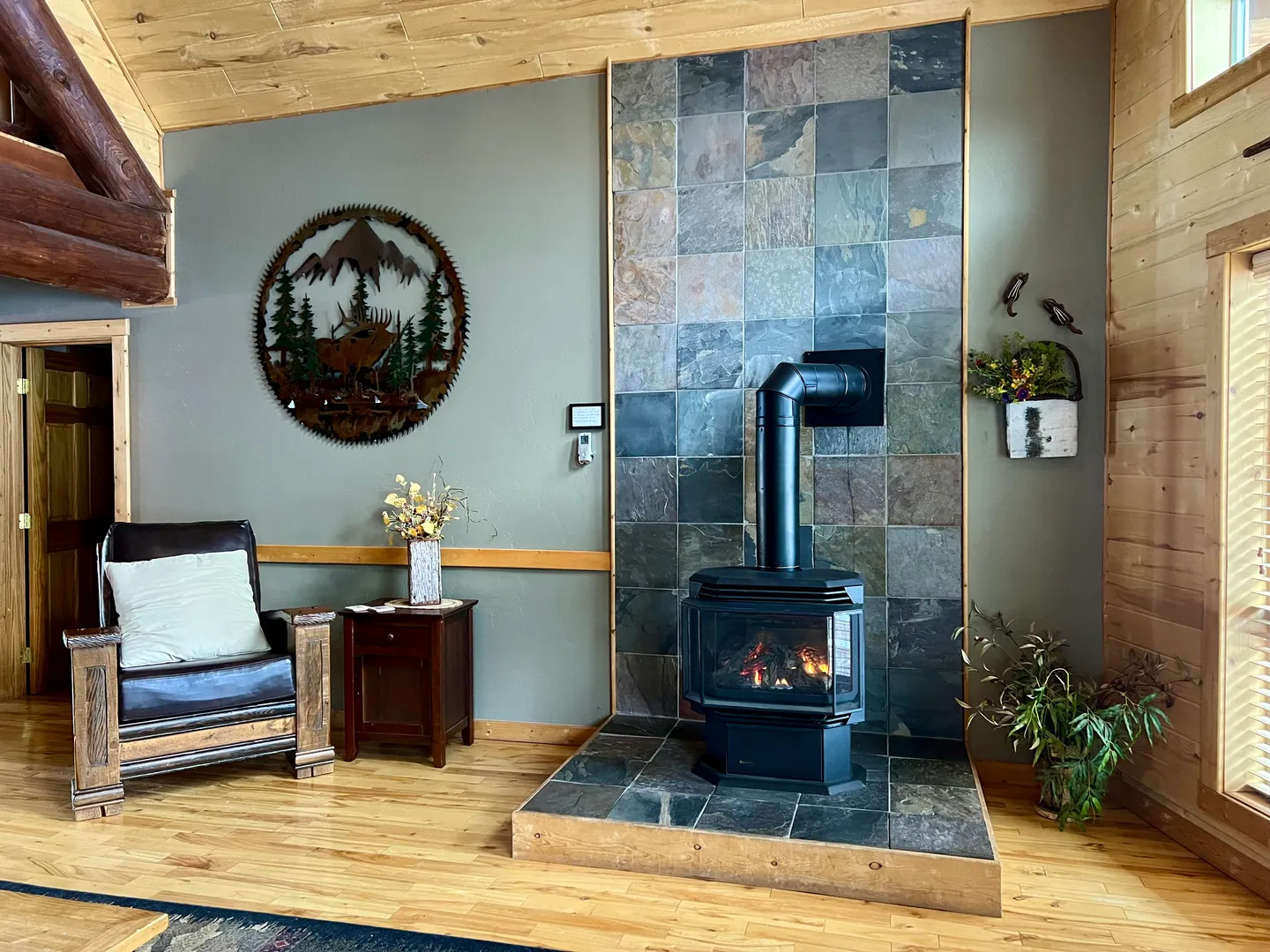 Freestanding wood-burning or gas stove on a raised slate hearth with a floor-to-ceiling slate tile accent wall.