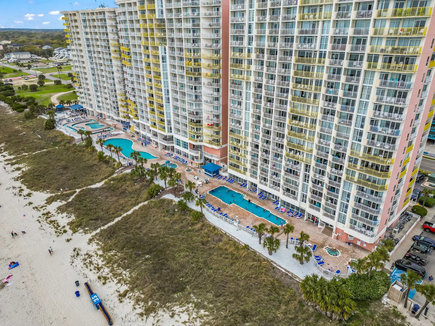 Aerial view of a beachfront high-rise resort building with multiple outdoor pools and direct beach access.