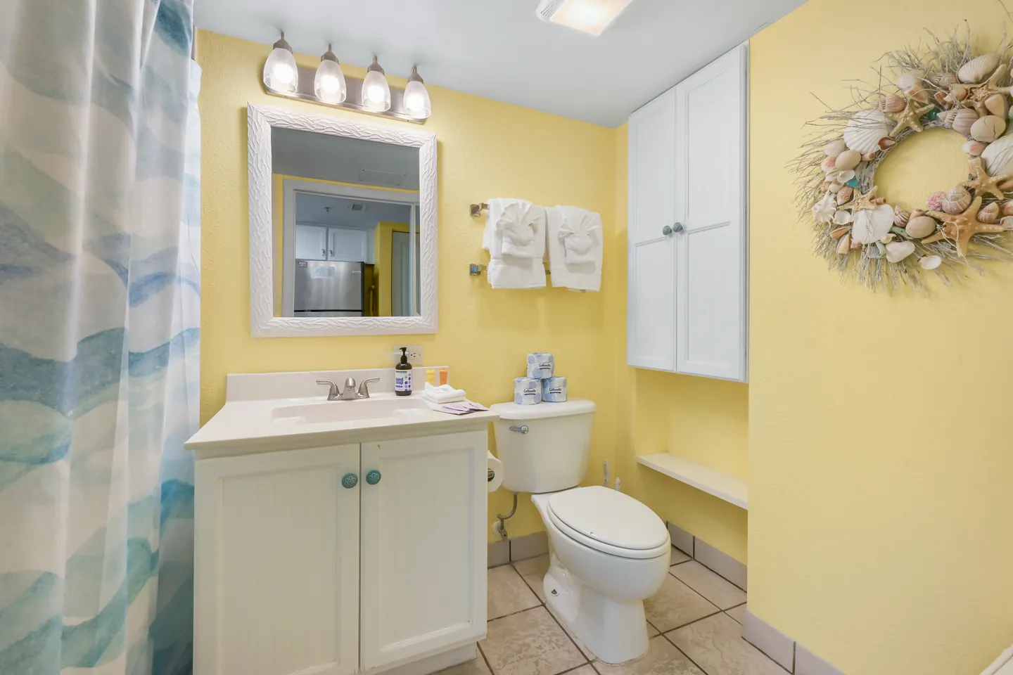 Bathroom with bright yellow walls, a white vanity with mirror, a toilet, and a white storage cabinet.