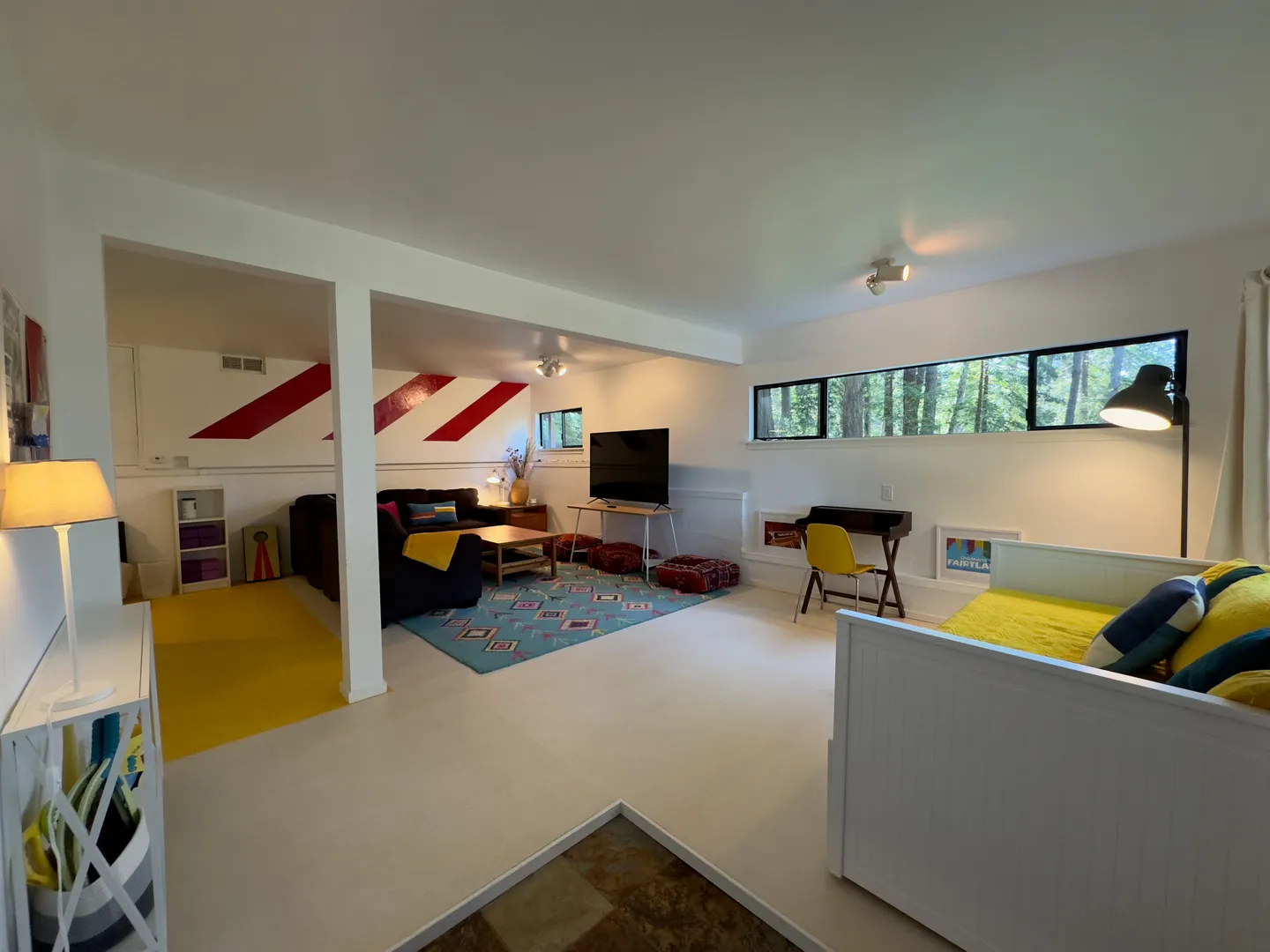 Open multipurpose room with a sitting area, television, desk, and a daybed.