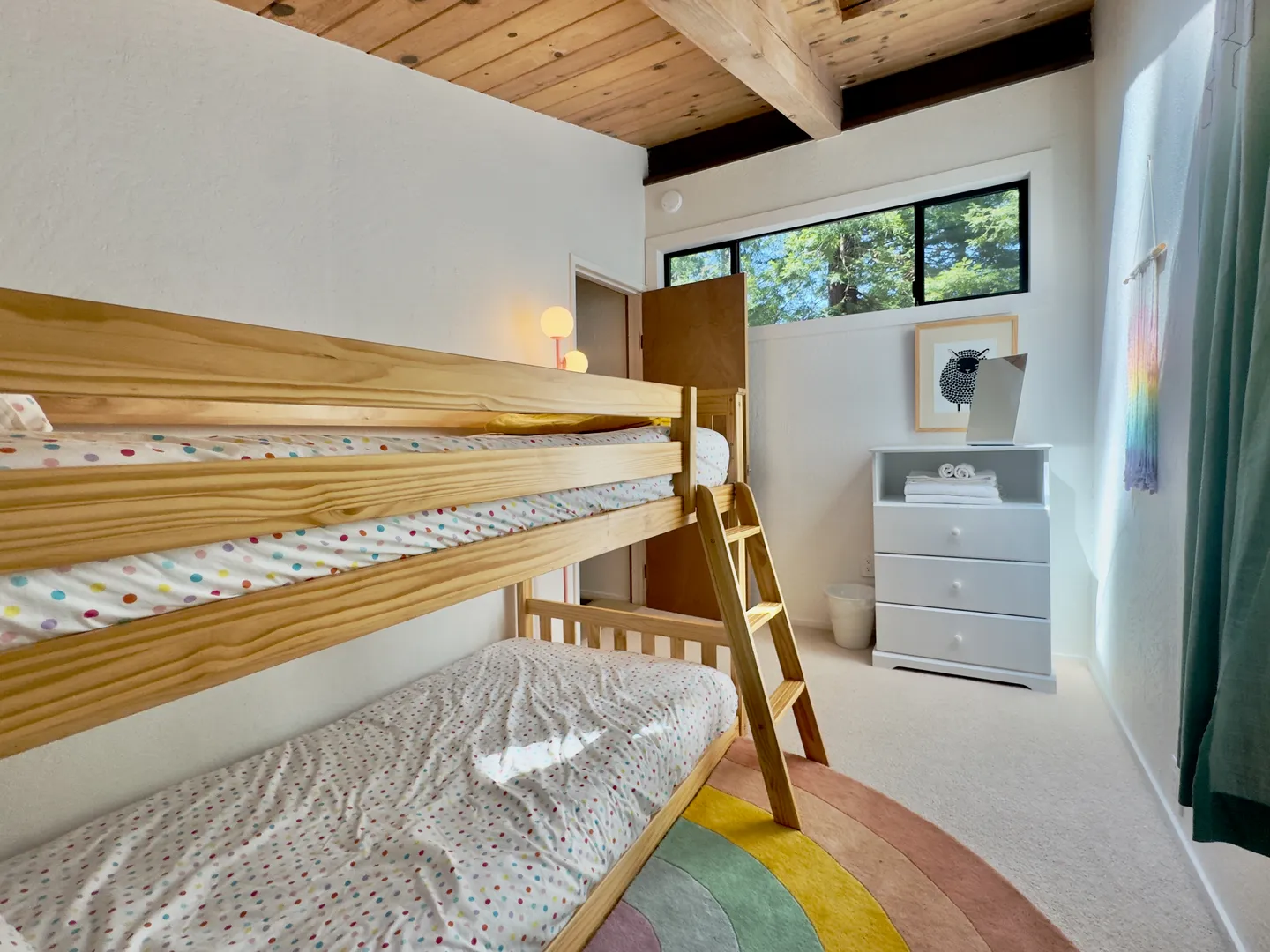 Bedroom featuring wooden bunk beds with polka-dot bedding, a wood-paneled ceiling with beams, and a white dresser beneath high windows.