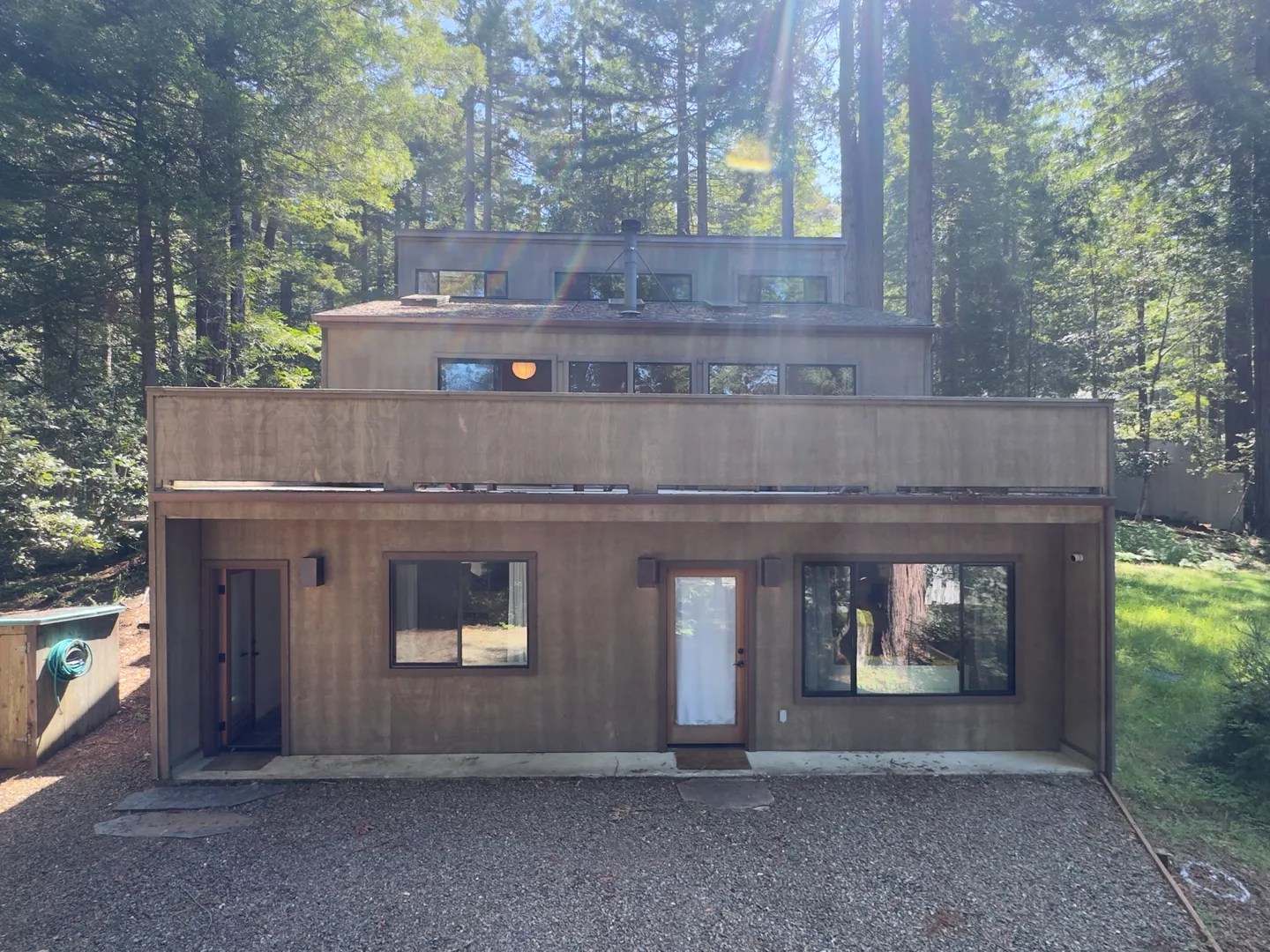 Exterior view of a multi-level wood-sided home surrounded by tall trees.
