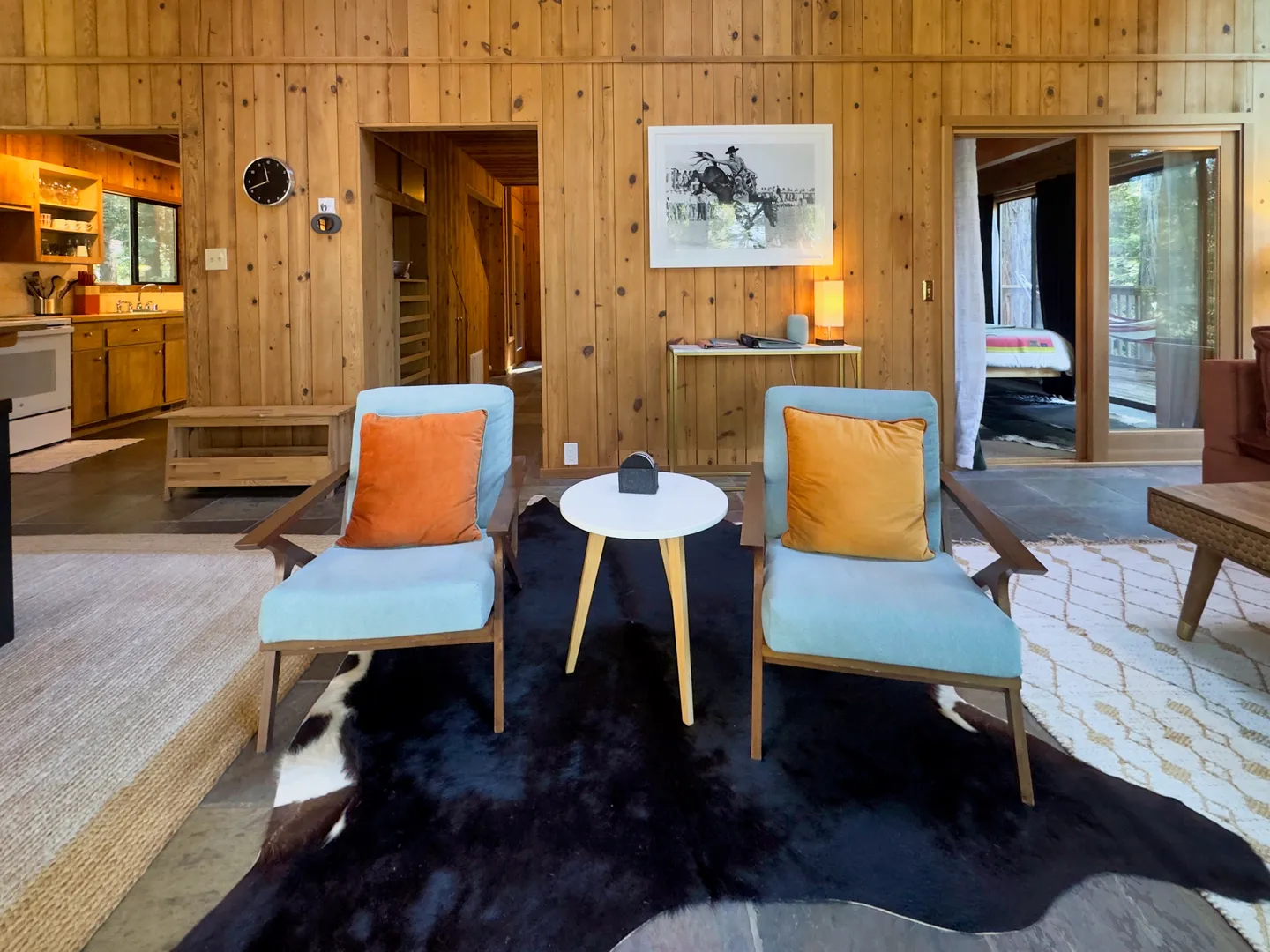 Living area featuring two light blue armchairs, a cowhide rug, and vertical wood-paneled walls.