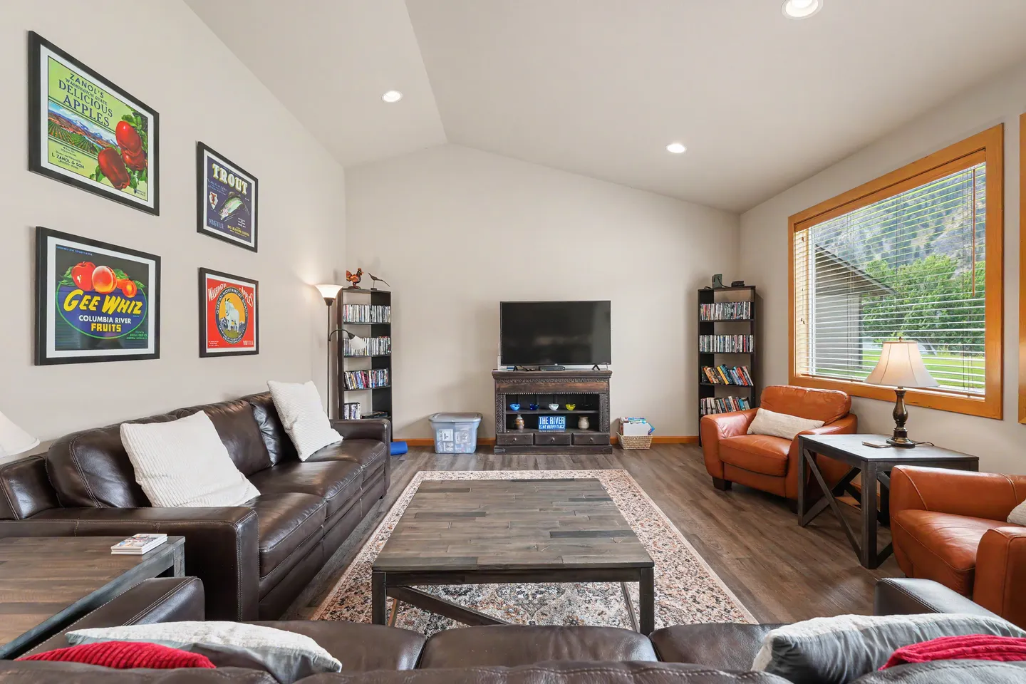 Living room with leather sofas, armchair seating, a large coffee table, and a TV on a rustic stand.