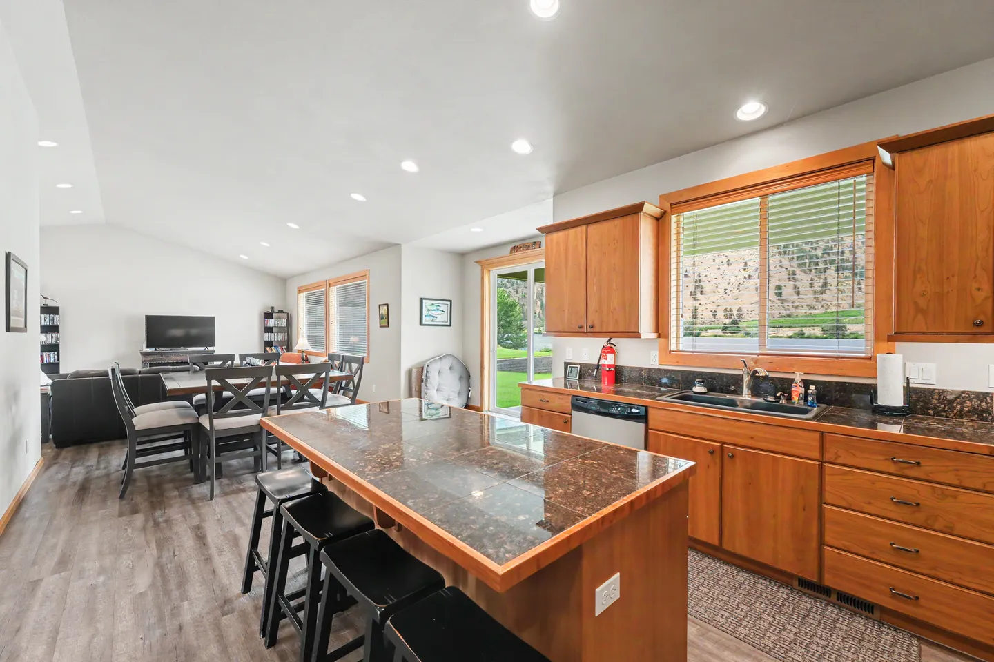 Open-concept kitchen and dining area featuring wooden cabinets, a central island with barstools, and views into the adjacent living space.