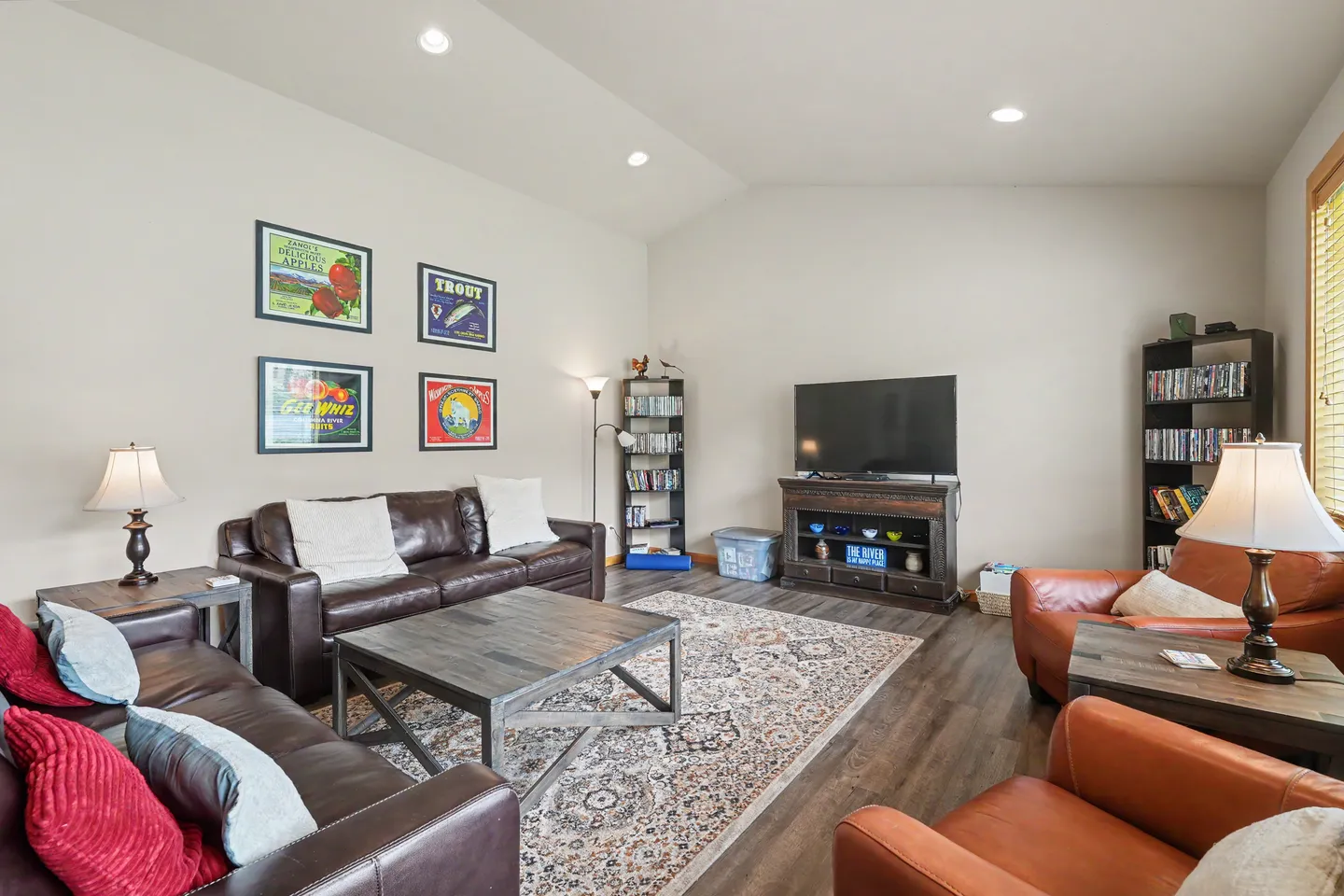 Living room with leather couches, leather armchairs, an area rug, and a television set on a media console.