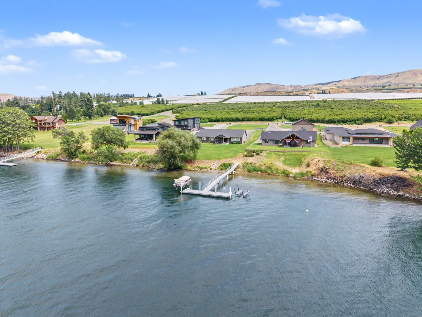 Aerial view of a lakefront neighborhood featuring private boat docks and surrounding orchards.