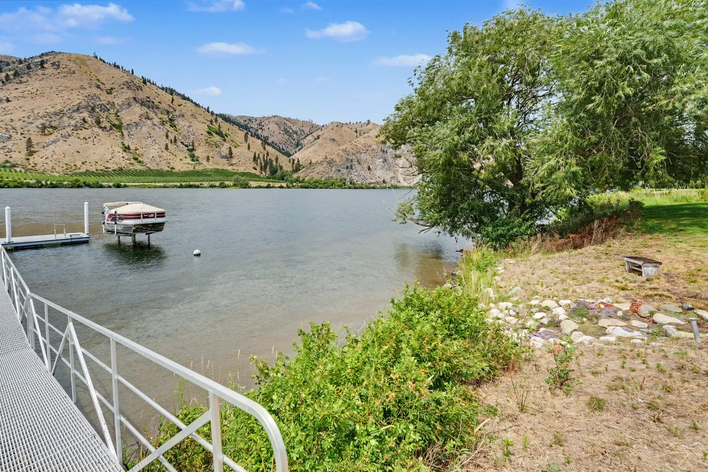 A metal dock ramp leading to a floating dock on a lake with arid hills in the background.