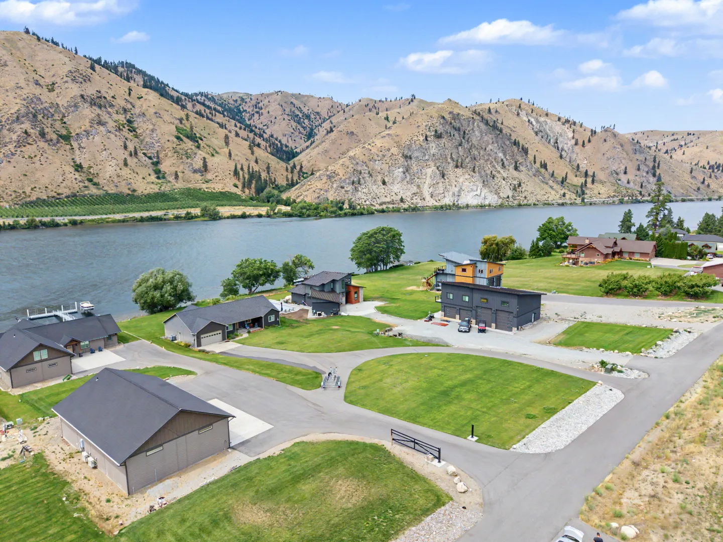 Aerial view of a neighborhood of homes along a river bordered by hills and mountains.