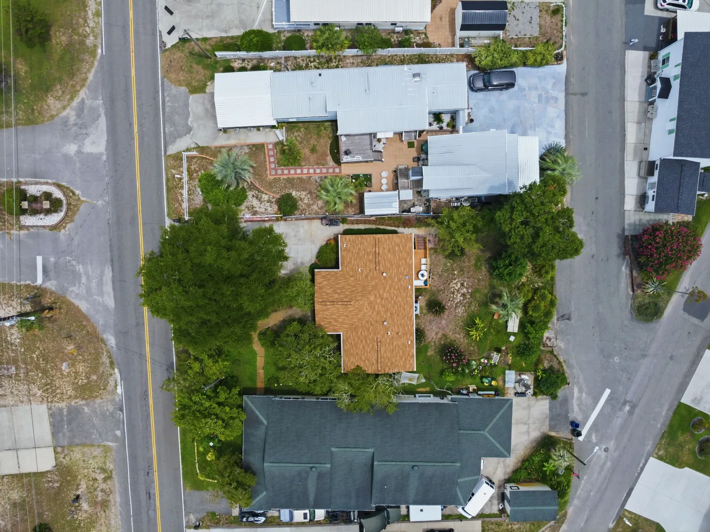 Direct overhead aerial view of residential houses, rooftops, paved roads, and landscaped yards.