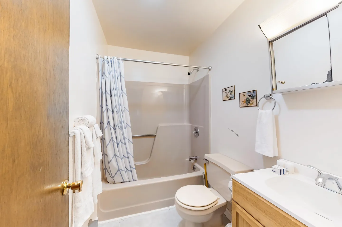 Bathroom with a bathtub shower combination, toilet, and vanity sink with a medicine cabinet.