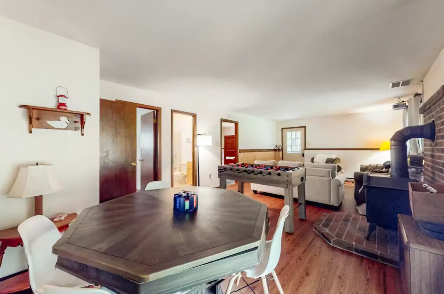 Game room and lounge area with an octagonal table, foosball table, wood stove, and sofa seating.