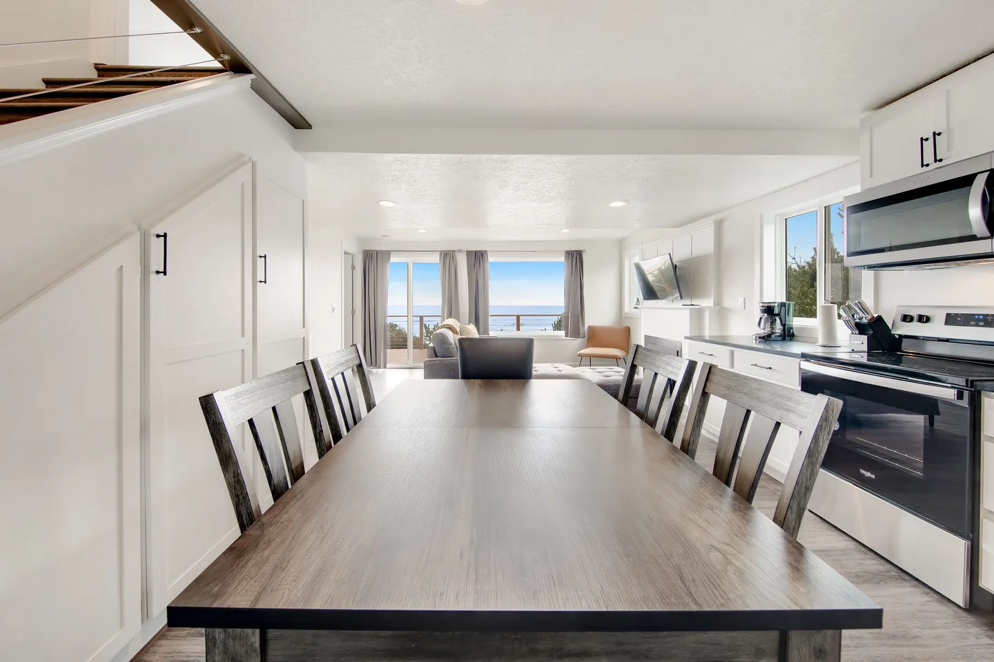 Open-concept dining and kitchen area leading into a living room with water views through large windows.