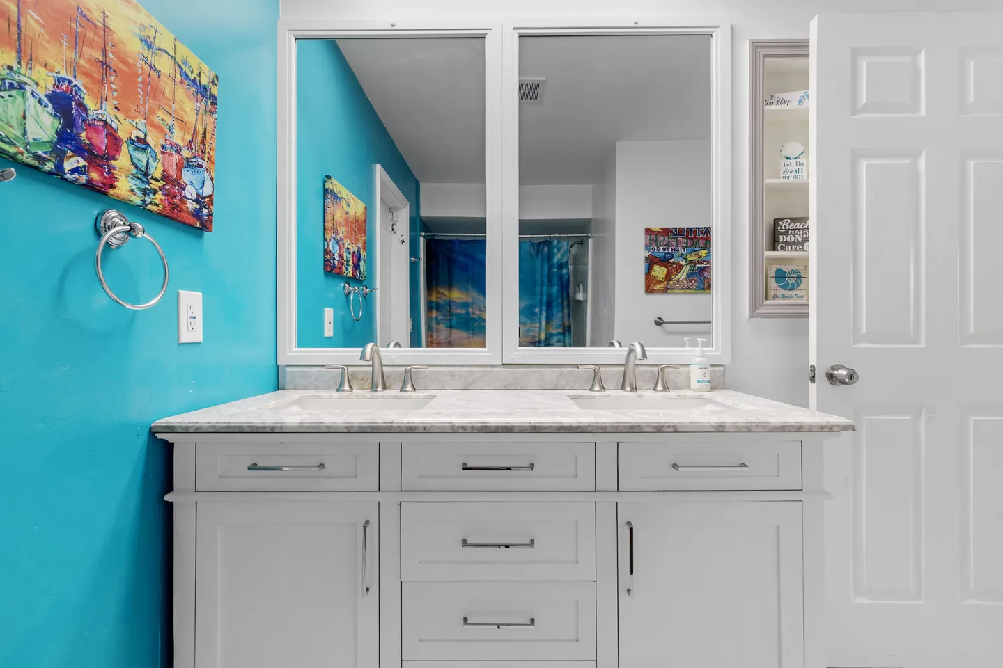 A bathroom vanity with a double sink, white cabinetry, light countertop, two mirrors, and turquoise wall.