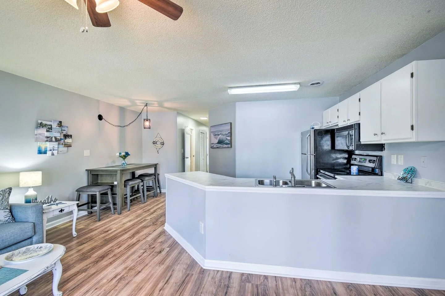 Open-concept kitchen and dining area with wood-look flooring, light blue walls, and white cabinetry.