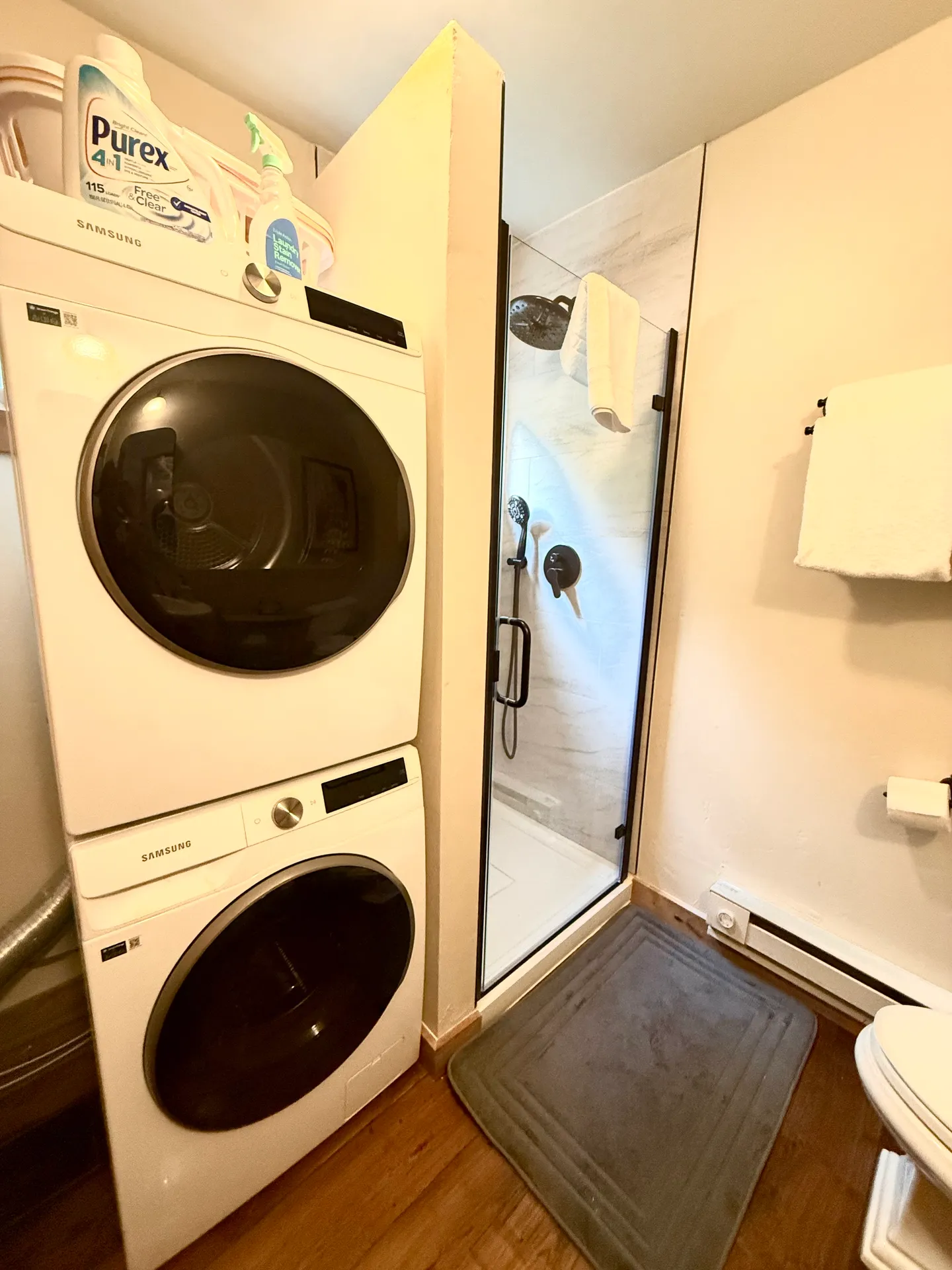 Bathroom with a stacked Samsung washer and dryer next to a glass-door walk-in shower.