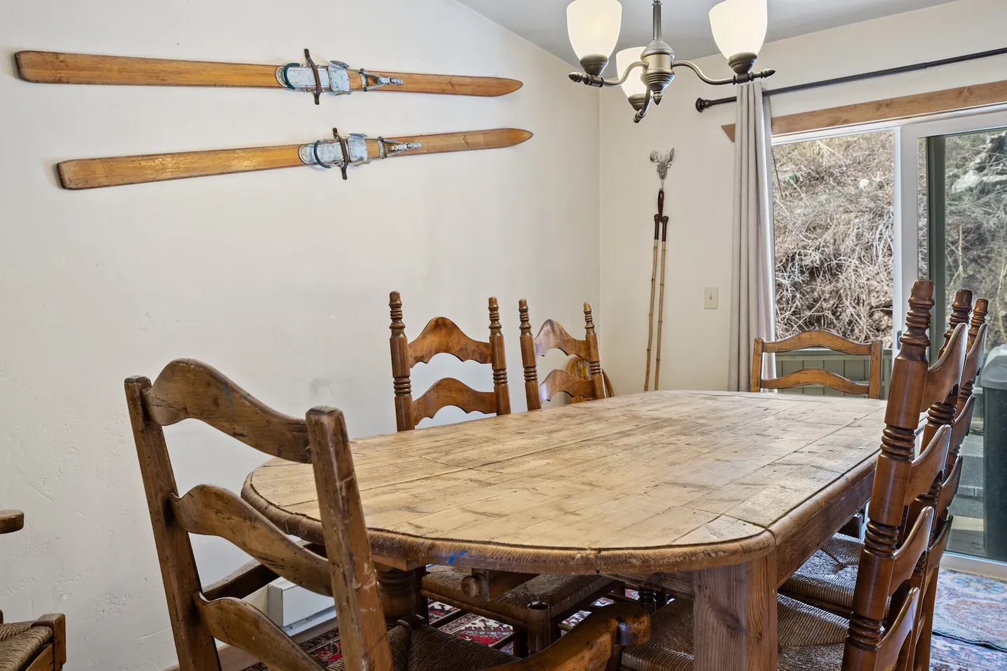 Dining area featuring a rustic wooden table and matching wooden chairs, decorated with vintage skis mounted on the wall.