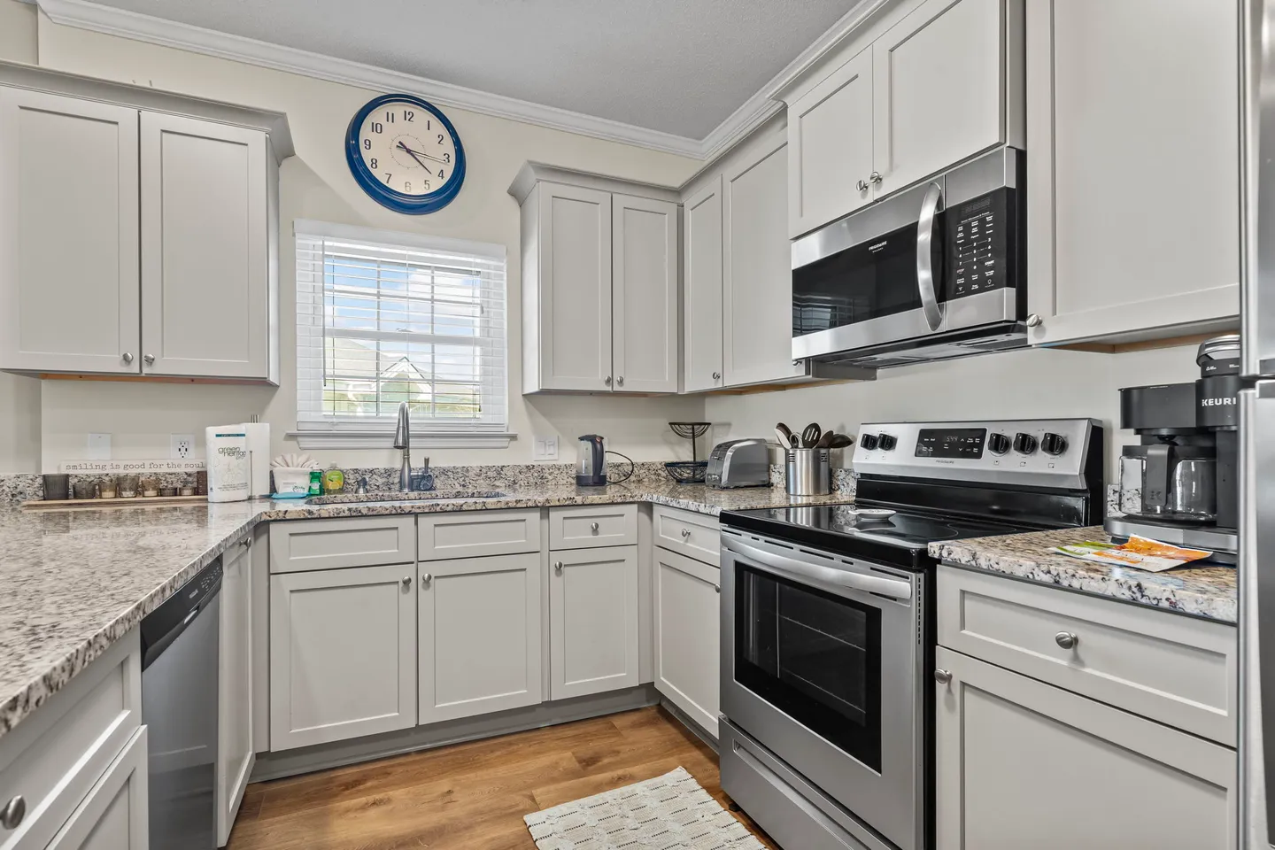 Kitchen featuring light gray shaker cabinets, speckled granite countertops, and stainless steel appliances.