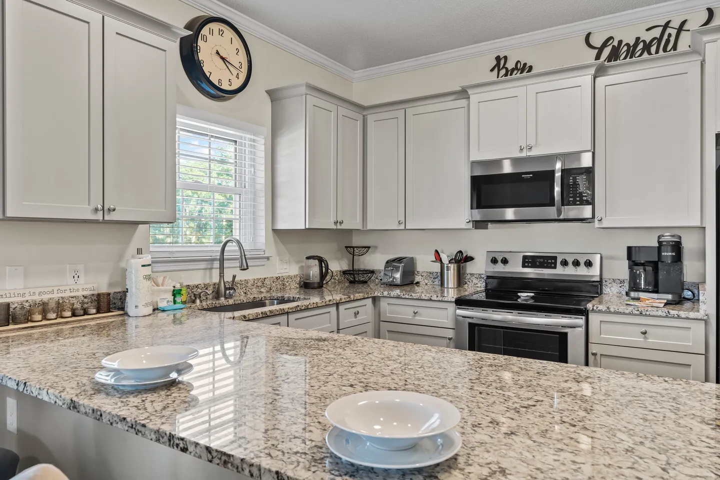 Kitchen counter and cabinets featuring speckled stone countertops, an undermount sink, and stainless steel appliances.