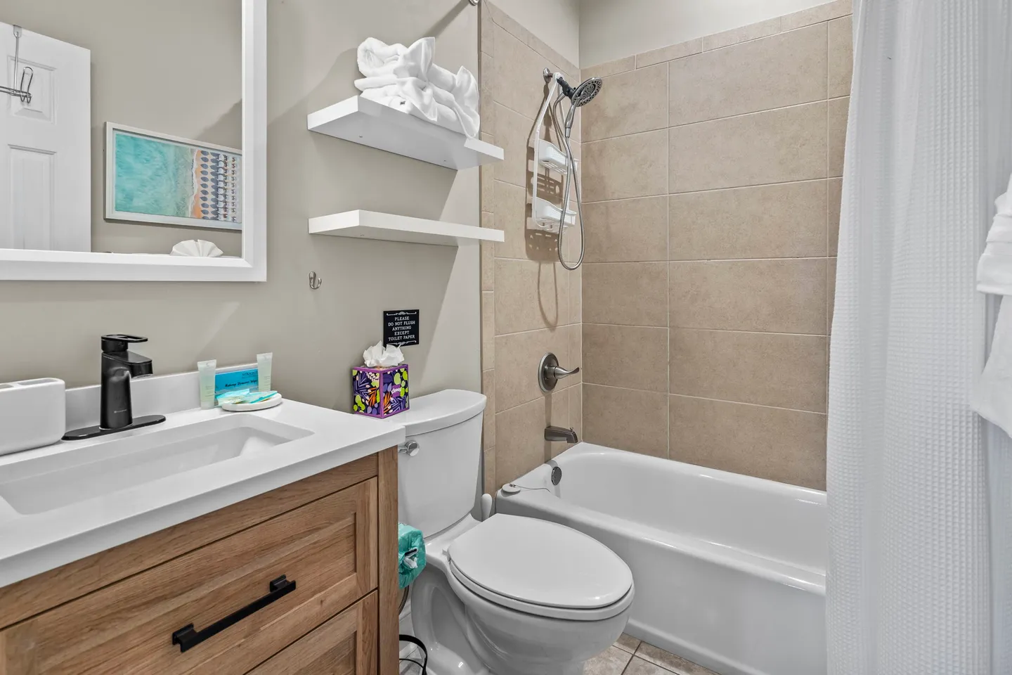 Bathroom with a vanity, toilet, and bathtub with a tiled shower surround.