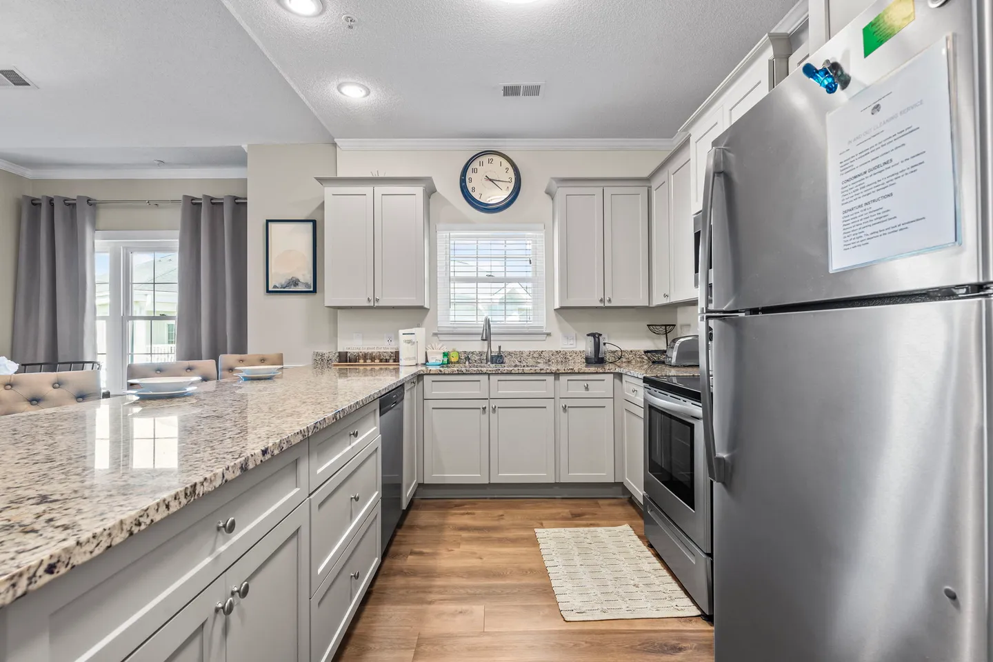 Kitchen with speckled countertops, light gray cabinets, stainless steel appliances, and wood-look flooring.