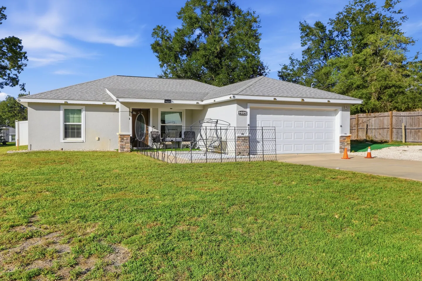 Exterior view of a single-story home featuring a two-car garage, front lawn, and paved entry patio.