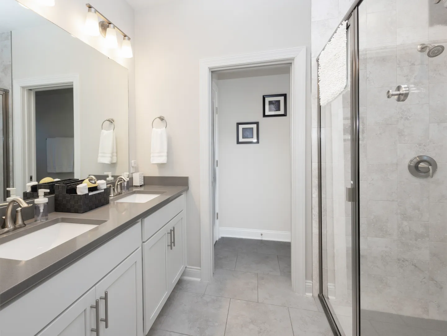 Bathroom featuring a double vanity with gray countertops and a glass-enclosed walk-in shower.