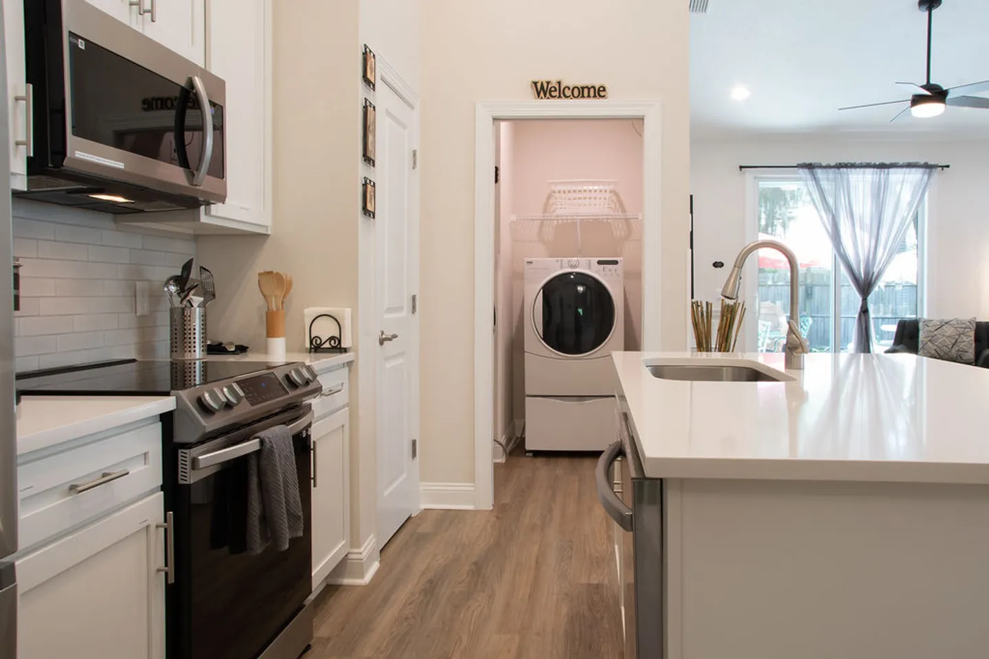 Kitchen with white cabinetry, stainless steel appliances, an island, and a doorway showing a laundry machine.