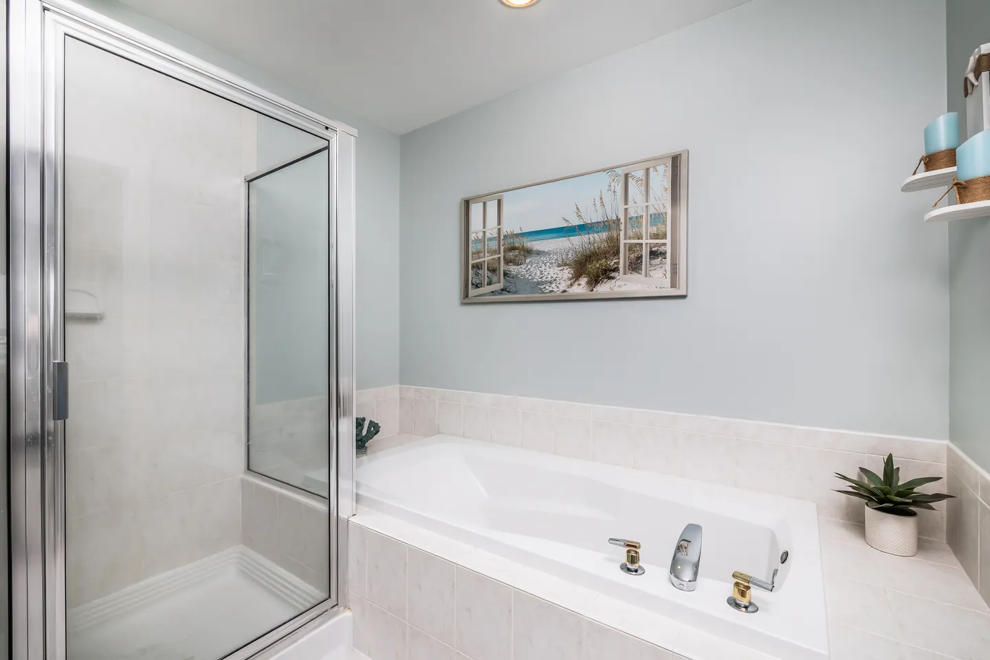 Bathroom featuring a white drop-in bathtub with tile surround next to a glass-enclosed shower stall.