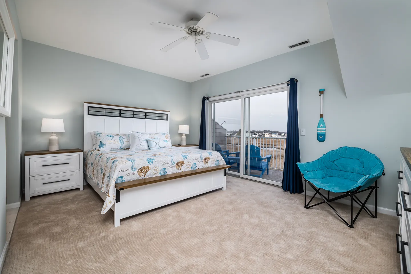 Bedroom with a white panel bed, carpeted floor, ceiling fan, and sliding glass doors leading to a balcony.