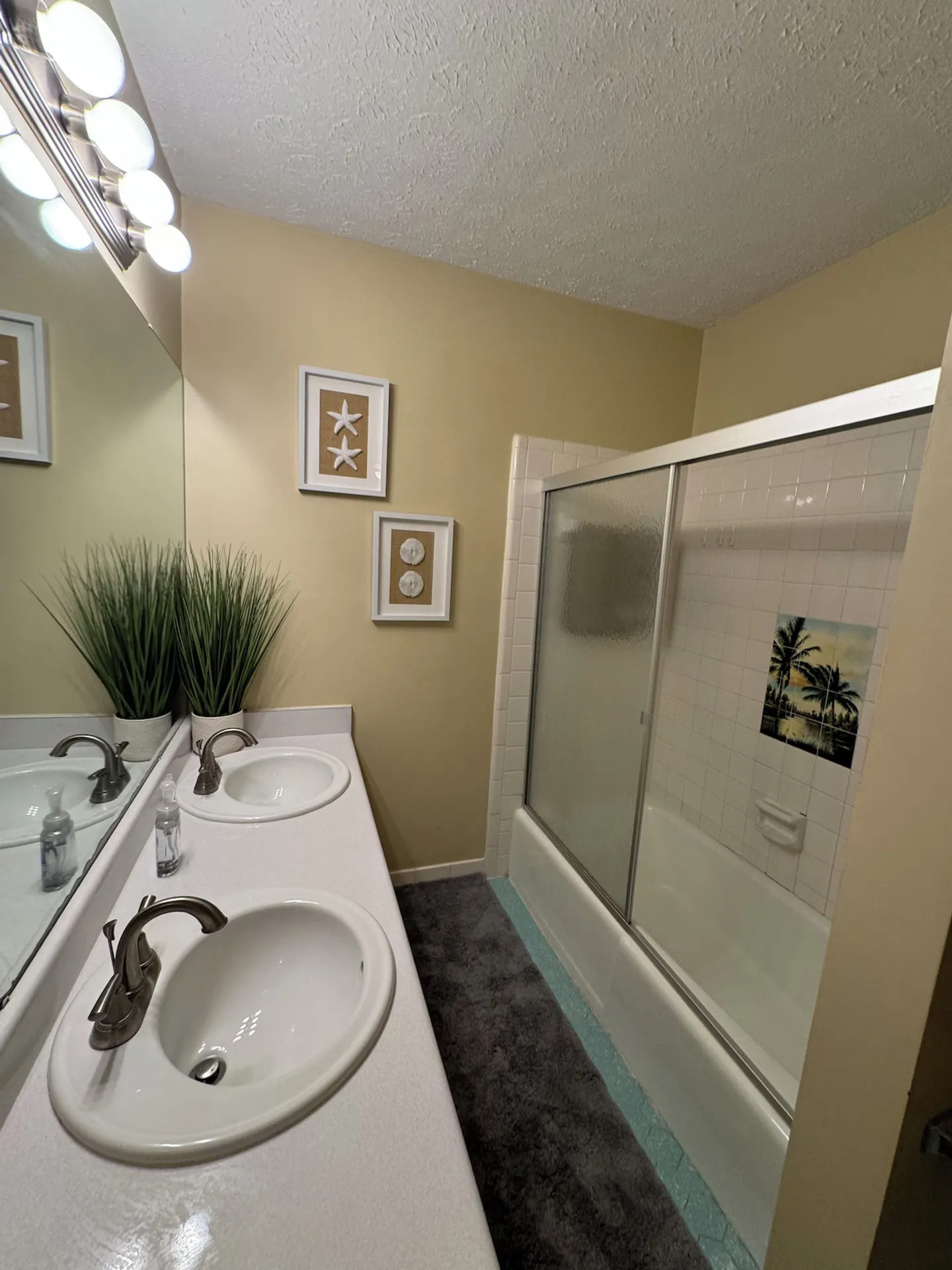 Bathroom with a double-sink vanity, large wall mirror, and a combination bathtub and shower with sliding glass doors.