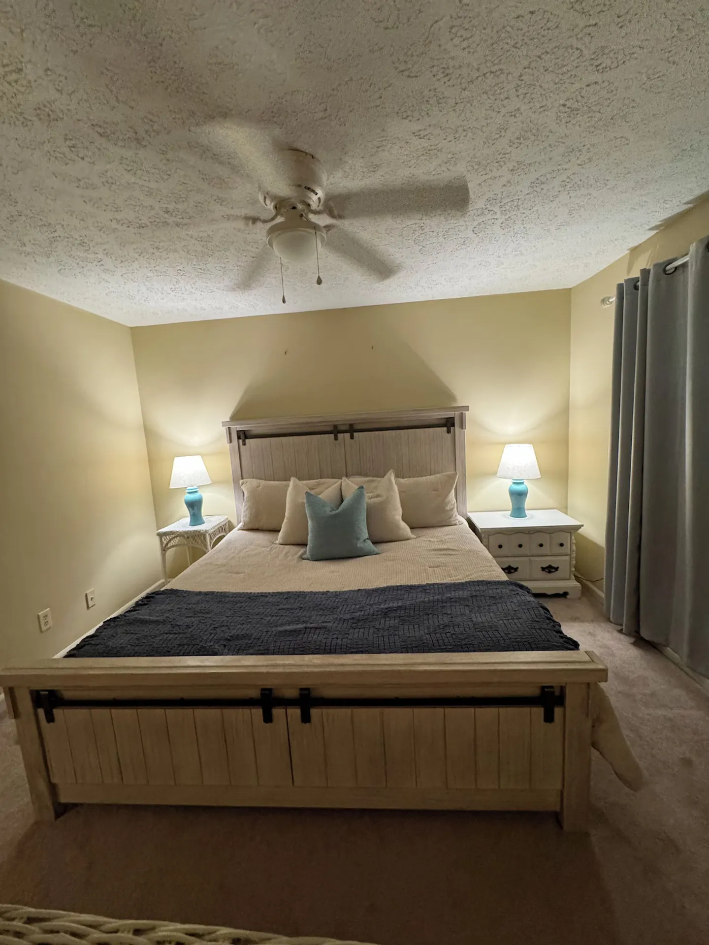 Bedroom featuring a light wooden barn-style bed frame flanked by nightstands with glowing blue lamps.