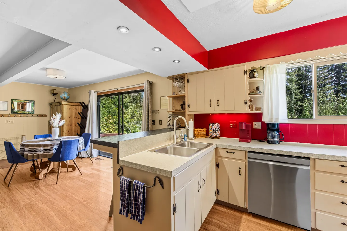 Kitchen counter and sink area looking toward an open dining space with a table, chairs, and sliding glass door.