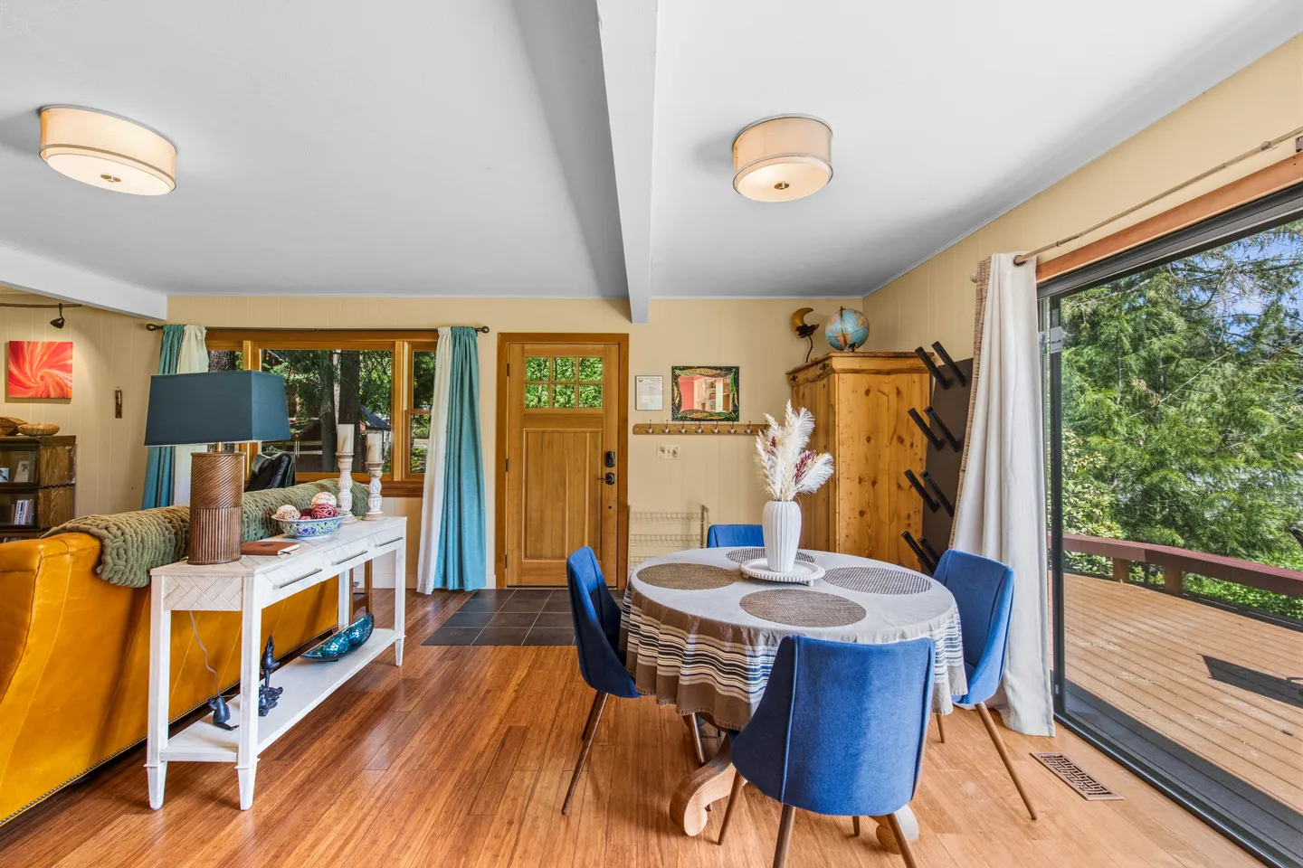 Dining area with a round table and blue chairs next to a sliding glass door leading to an outdoor deck.