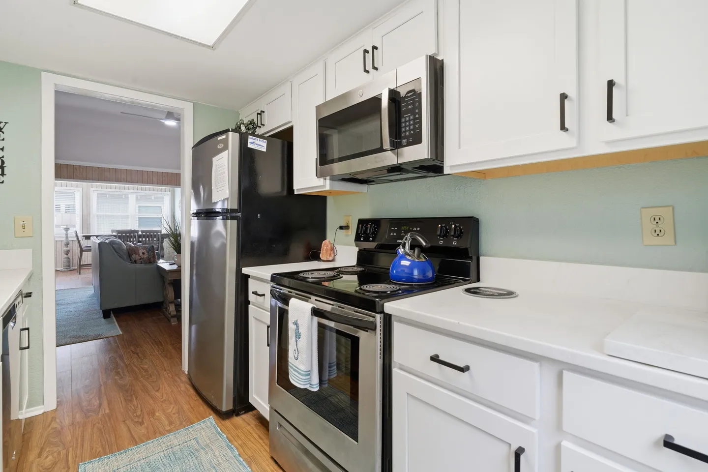 Kitchen with white cabinetry, stainless-steel appliances, and a view into the living room.