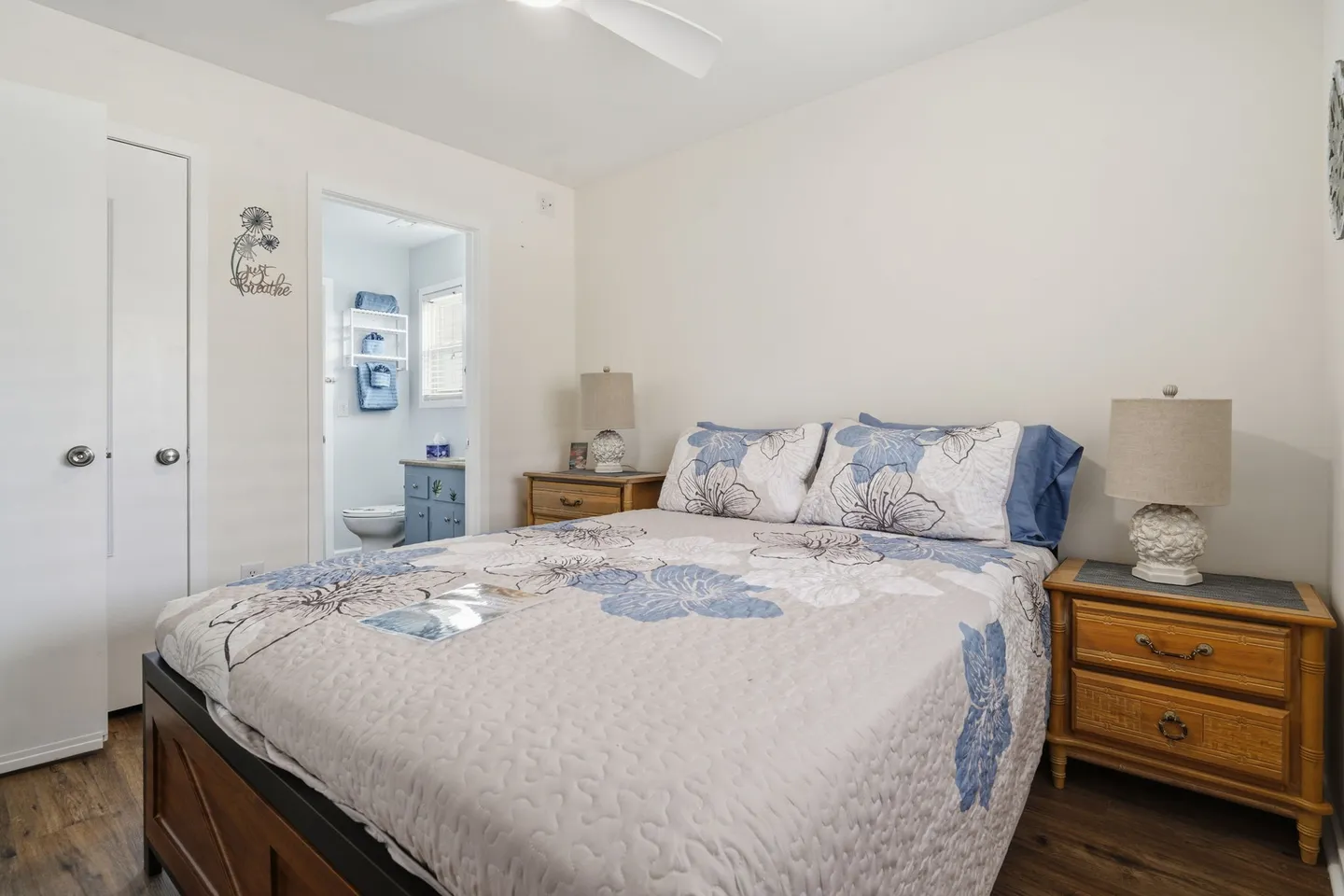Bedroom with a double bed flanked by two wooden nightstands, offering a view into an attached bathroom.