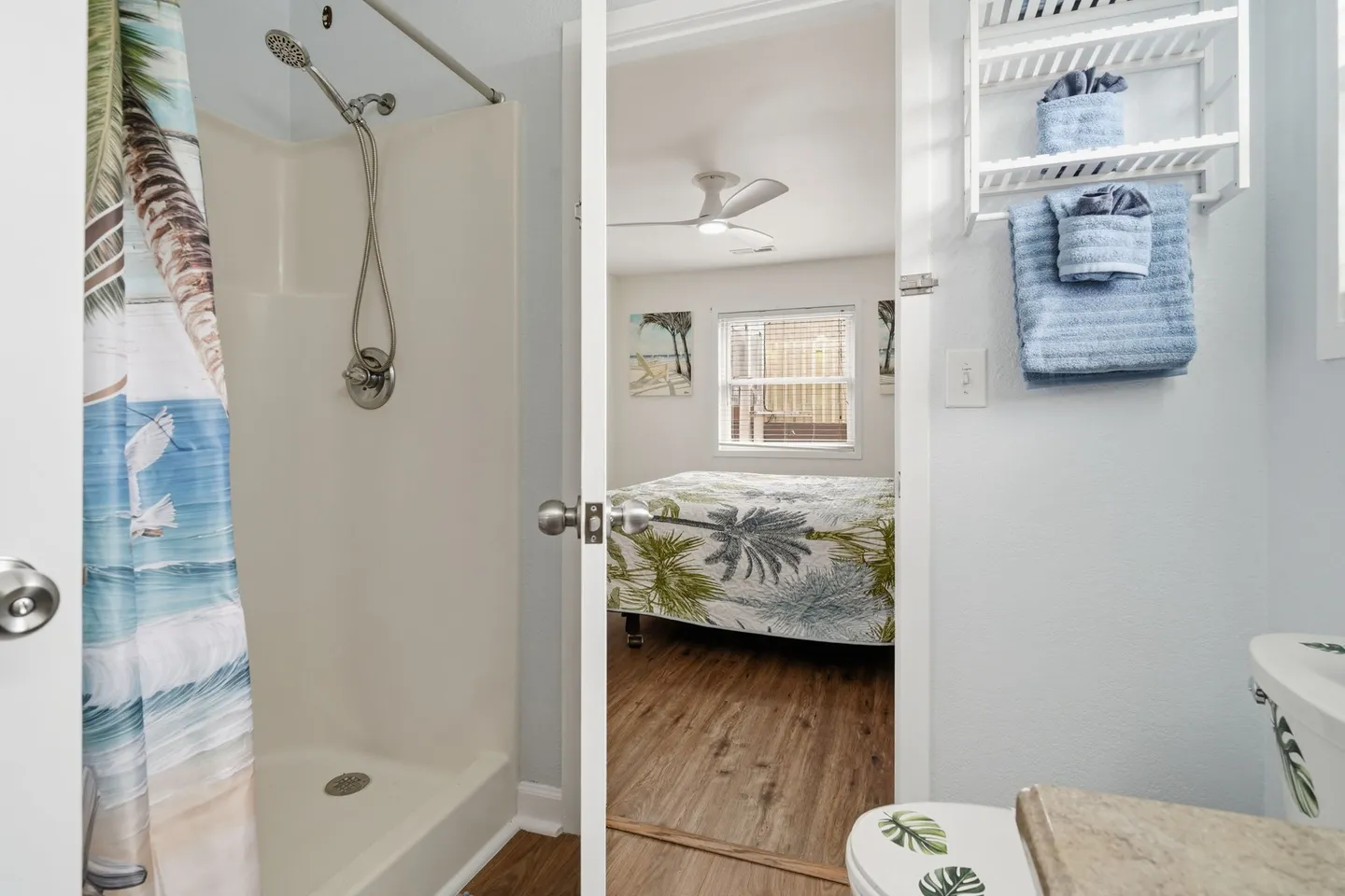 Bathroom with a walk-in shower stall, looking through an open doorway into an adjoining bedroom.