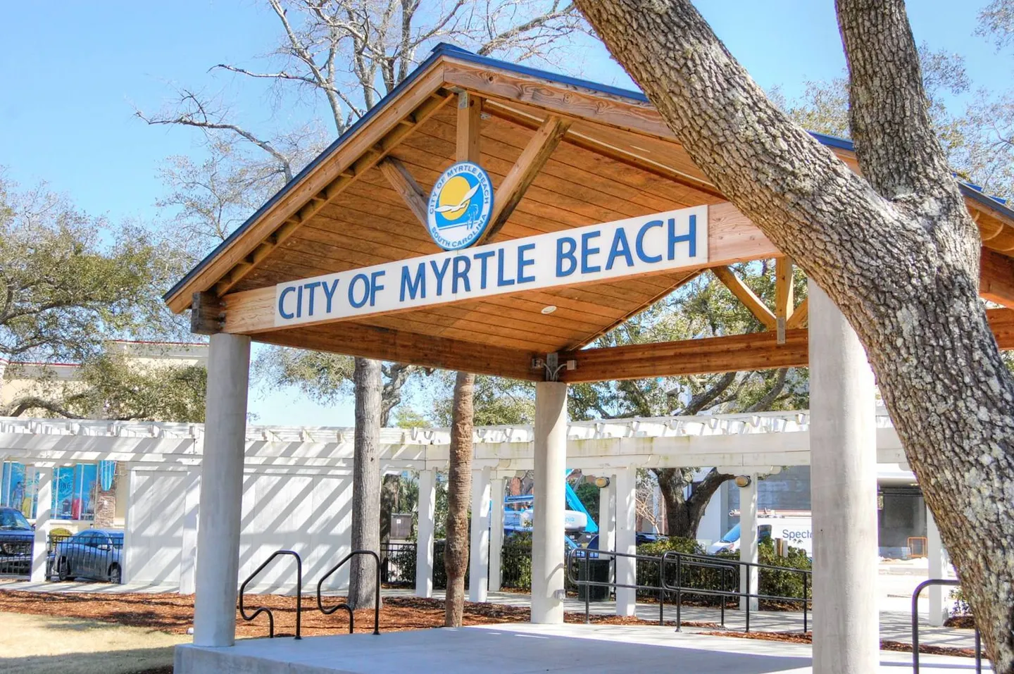 A covered outdoor stage pavilion with concrete pillars, wood rafters, and a sign reading City of Myrtle Beach South Carolina.