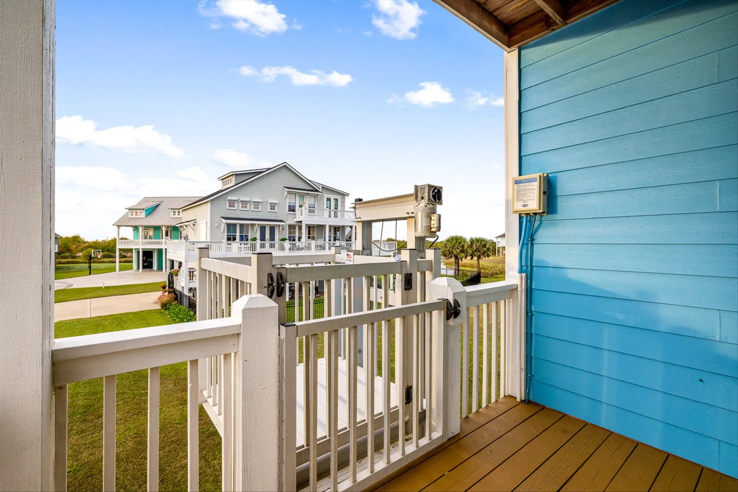 Exterior deck featuring an outdoor cargo lift or elevator with white safety railings and a view of neighboring houses.