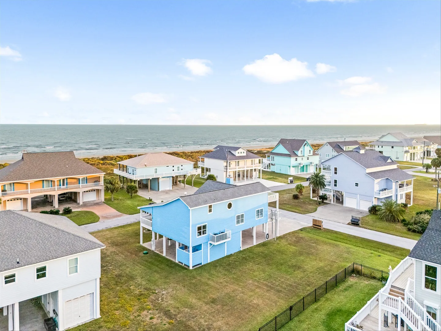 Aerial view of a coastal neighborhood with stilt homes near the ocean and beach.