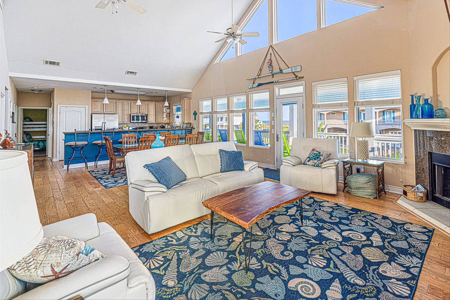 Open-concept living room with vaulted ceilings, large windows, a white sofa, and a view into the kitchen and dining area.